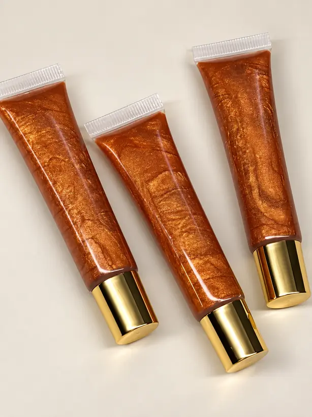 Three Bronze Glow lip gloss tubes with gold caps